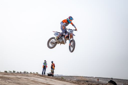 motorcross riding motorbike on sandy track during the day jumping