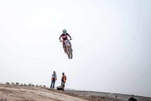 motorcross riding motorbike on sandy track during the day jumping