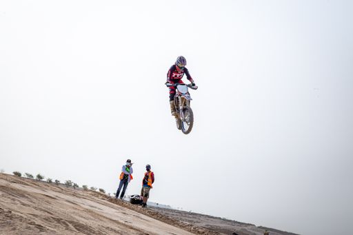 motorcross riding motorbike on sandy track during the day jumping