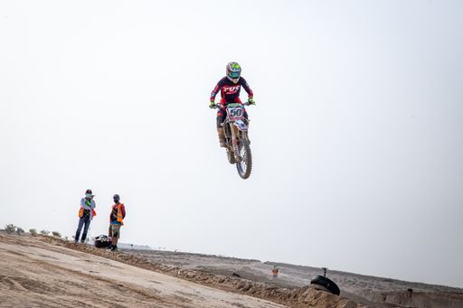motorcross riding motorbike on sandy track during the day jumping