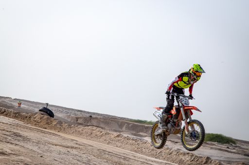 motorcross riding motorbike on sandy track during the day jumping