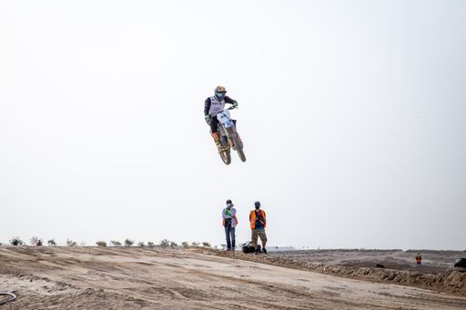motorcross riding motorbike on sandy track during the day jumping