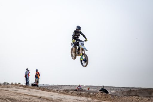 motorcross riding motorbike on sandy track during the day jumping