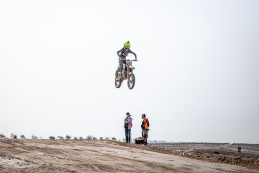 motorcross riding motorbike on sandy track during the day jumping
