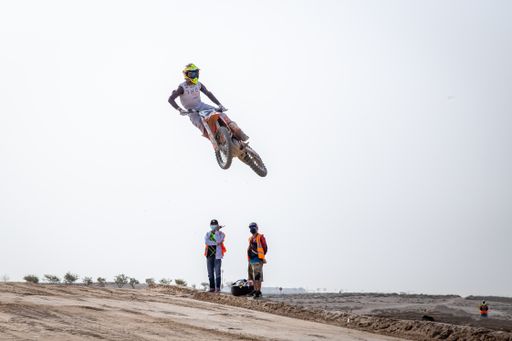 motorcross riding motorbike on sandy track during the day jumping