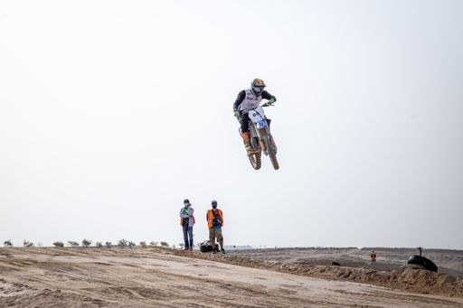 motorcross riding motorbike on sandy track during the day jumping
