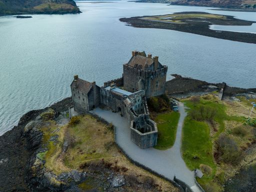 Aerial view of a historic Eilean Donan Castle Scotland situated atop a hill surrounded by blue water