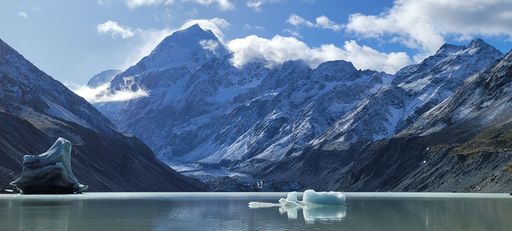 The large icebergs floating in a tranquil lake surrounded by snow capped mountains in the background