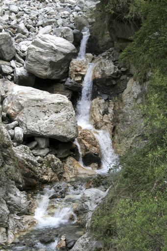 A vertical shot of a beautiful waterfall flowing through rocky cliffs