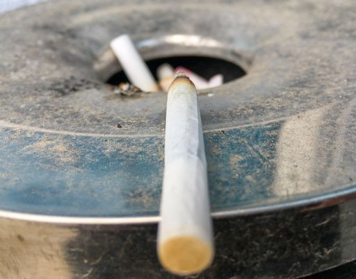A closeup of a used cigarette butt on the metal ashtray