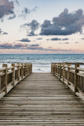 A vibrant vertical shot of a wooden pier extending into a body of water at a beach