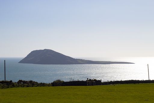 A natural view of a greenfield with Bardsey Island in the background