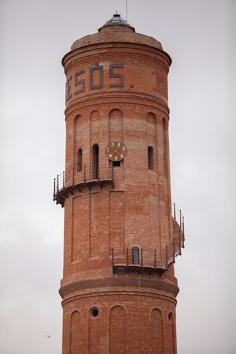 An old, rustic tower in Barcelona, Spain, set against a cloudy sky.