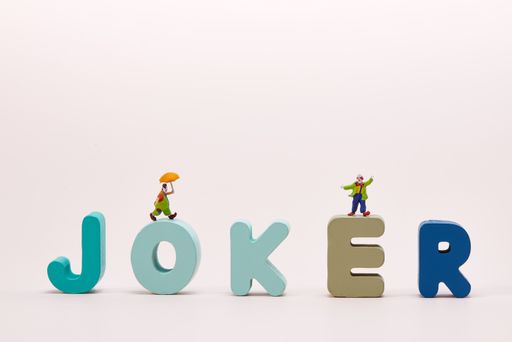 A wooden JOKER text with clown figurines isolated on white background