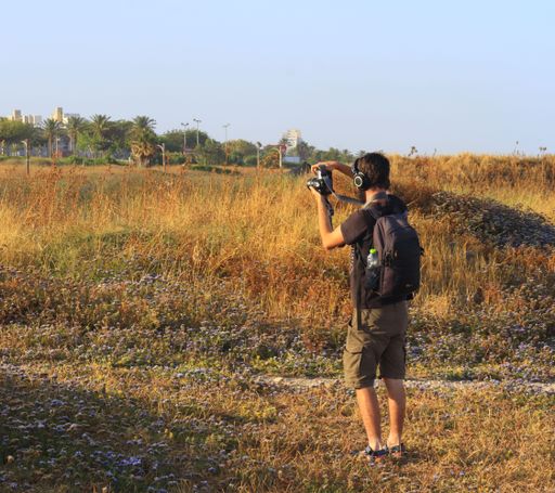 A young Caucasian man taking photos with his digital camera in the suburbs of a tropical town in the morning