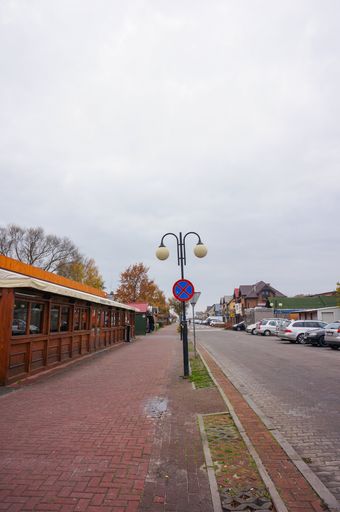 Street with restaurants and parked cars on a cloudy day