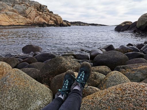 A closeup shot of a person sitting on the rocky shore of the sea