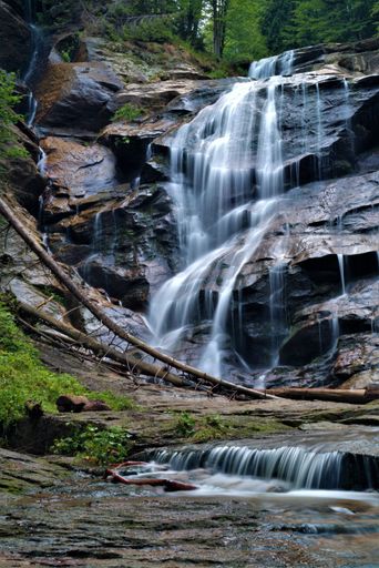 The cascades of a fast-flowing stream on mountain rocks, a small waterfall  - vertical shot