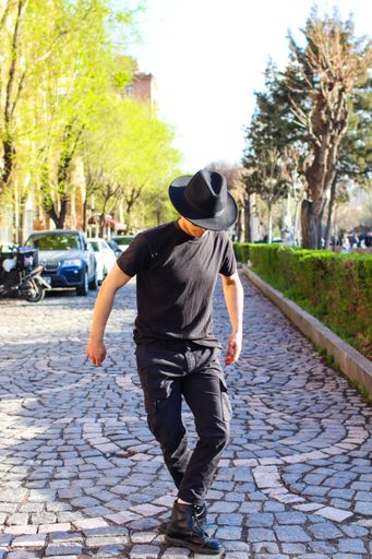 young man dancer in full black outfit dancing in the street on a sunny day
