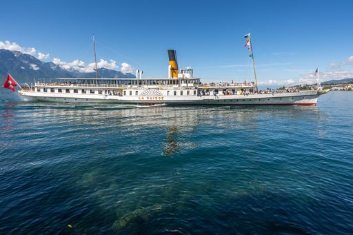 A large passenger boat sailing on Lake Geneva in Montreux, Switzerland, with several people on board