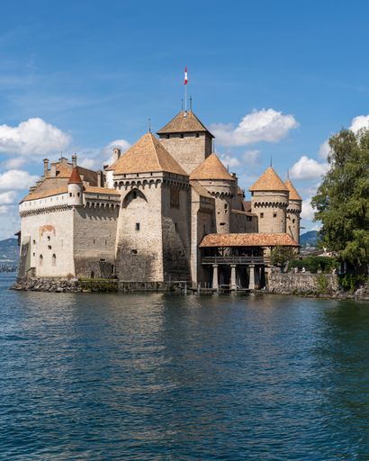 A scenic view of an idyllic island with several buildings and a flag flying proudly in the background