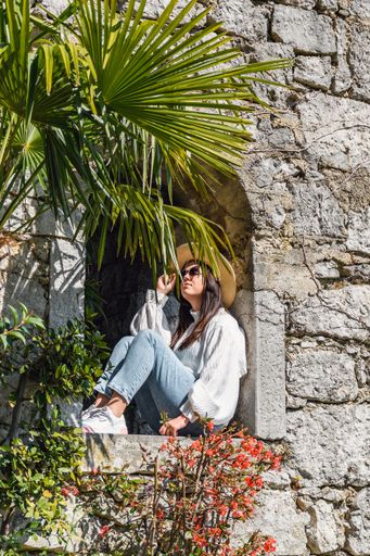 An adult woman sitting on a castle with the sea in the background on a sunny day in Croatia