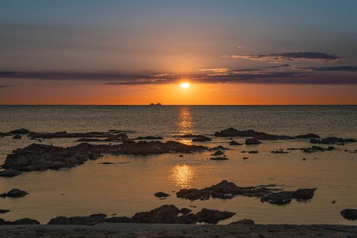 A beautiful view of the colorful skies during the sunset over the ocean and stones in it  Uruguay