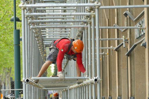 Worker building a scaffolding in renovation site wearing protective helme