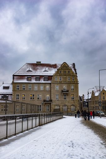 Footpath with barrier covered with snow leading to the Adam Mickiewicz university building on a cold winter day