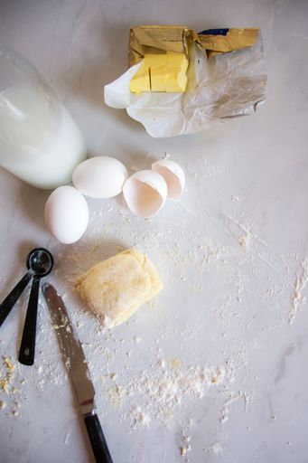 A kitchen countertop with flour and a few eggs, ready to be used in a culinary dish