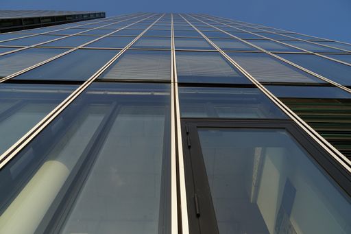 A low angle shot of a building with glass walls under the sunlight and a blue sky