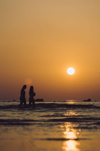The two people enjoy a romantic sunset while swimming in a tranquil sea