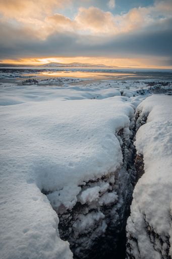 A breathtaking view of an icy snow-covered field in Reykjavik, Iceland during a stunning sunset