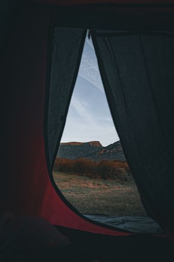 A tent illuminated in the darkness, with a mountainous landscape in the background