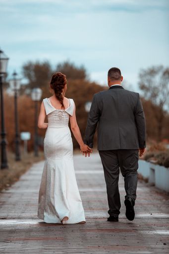 A beautiful view of a bride and groom walking into the park