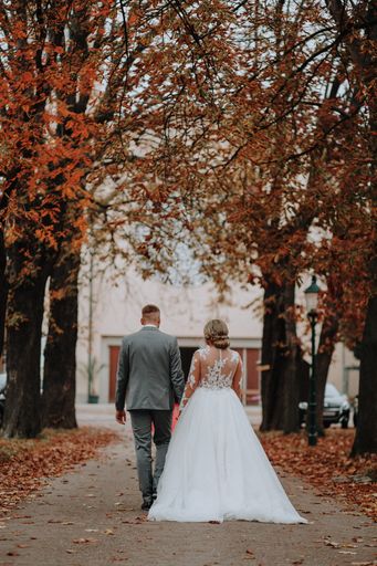 A beautiful view of a bride and groom walking into the park