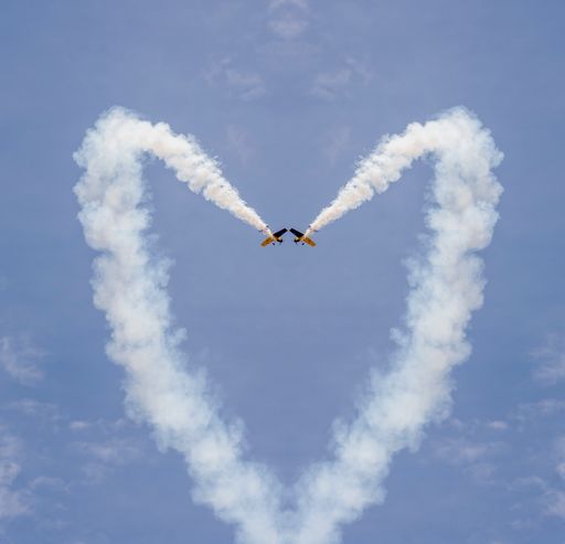 Two planes forming a heart shape with tracks on the blue sky