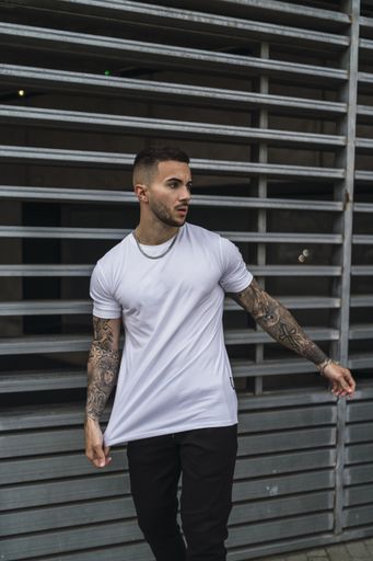 A vertical shot of a young European man with tattooed arms