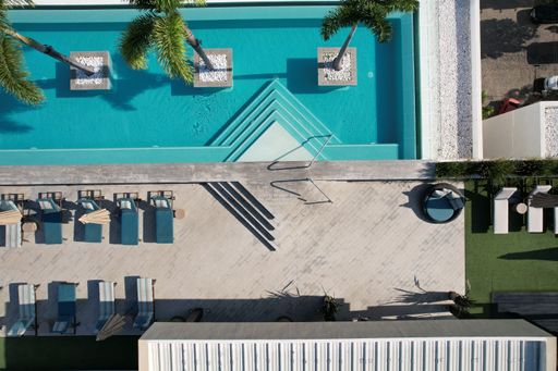 Aerial view of a pristine swimming pool surrounded by luxury beach chairs, inviting a perfect day in the sun
