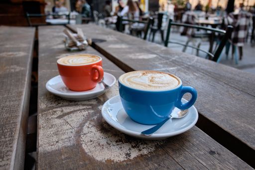 A closeup shot of two cups of latte coffee on a wooden surface