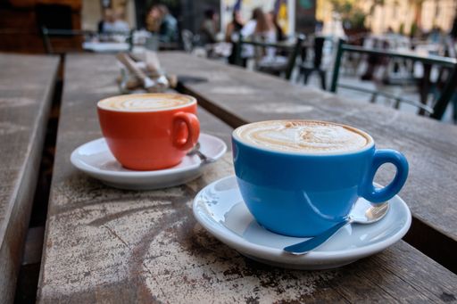 A closeup shot of two cups of latte coffee on a wooden surface