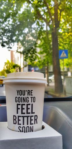 A closeup shot of disposable paper coffee cup with an inspirational quote to strengthen mental health