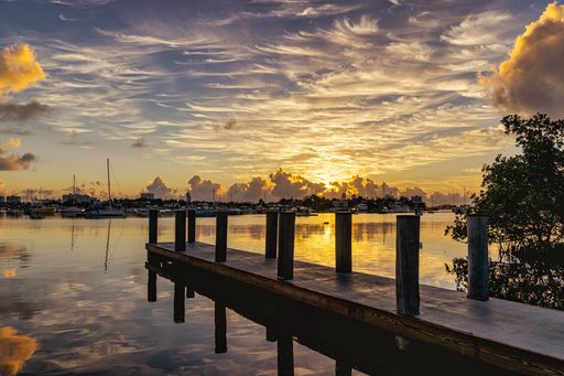 A beautiful view of the white clouds in the sky during sunset over the pier and the water