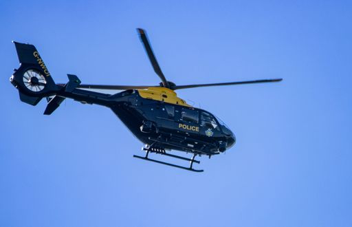 A low angle shot of a police helicopter flying over South Wales, the UK