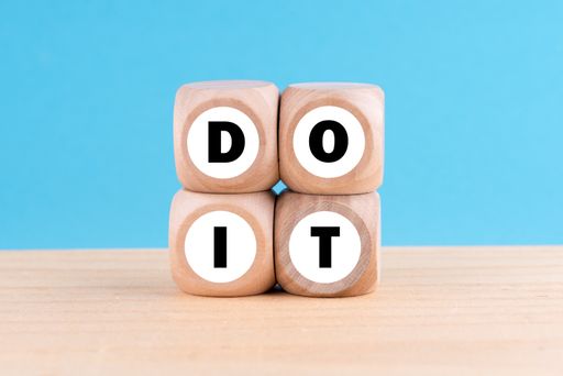The phrase DO IT formed with wooden blocks tower in the blue background/ motivational concept