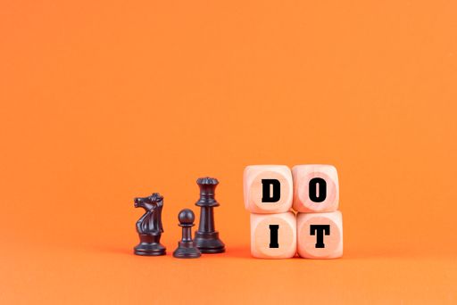 The chess pieces and phrase DO IT formed with wooden blocks in the orange background