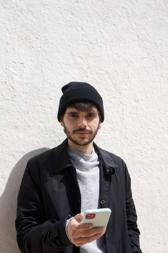 A stylish Spanish guy leaning on a wall and using his smartphone - people and technology concept