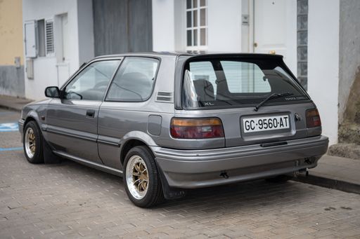 A gray classic Japanese car, the small Toyota Corolla XL EE90 parked on the street