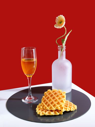High-resolution vertical shot of a delicious plate of waffles, accompanied by drinks, isolated against a vibrant red background