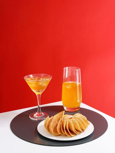 A vertical shot of appetizing snacks accompanied with drinks isolated on red background